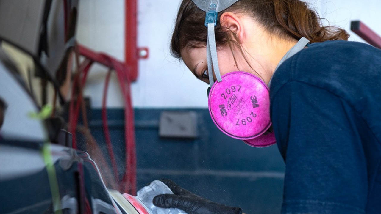 A welder using pink protective 3M equipment on their face.