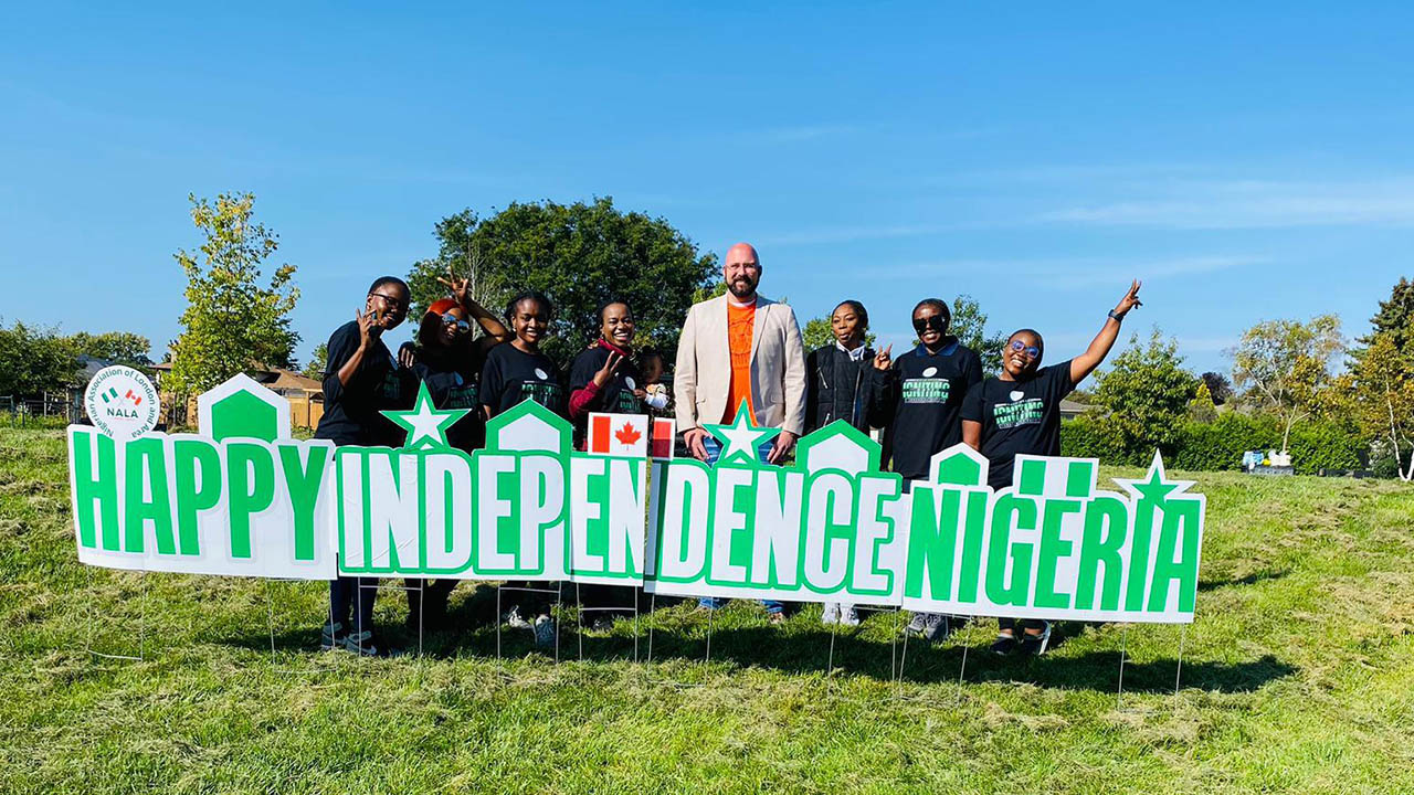 A group of eight people behind a sign that states: Happy Independence Nigeria