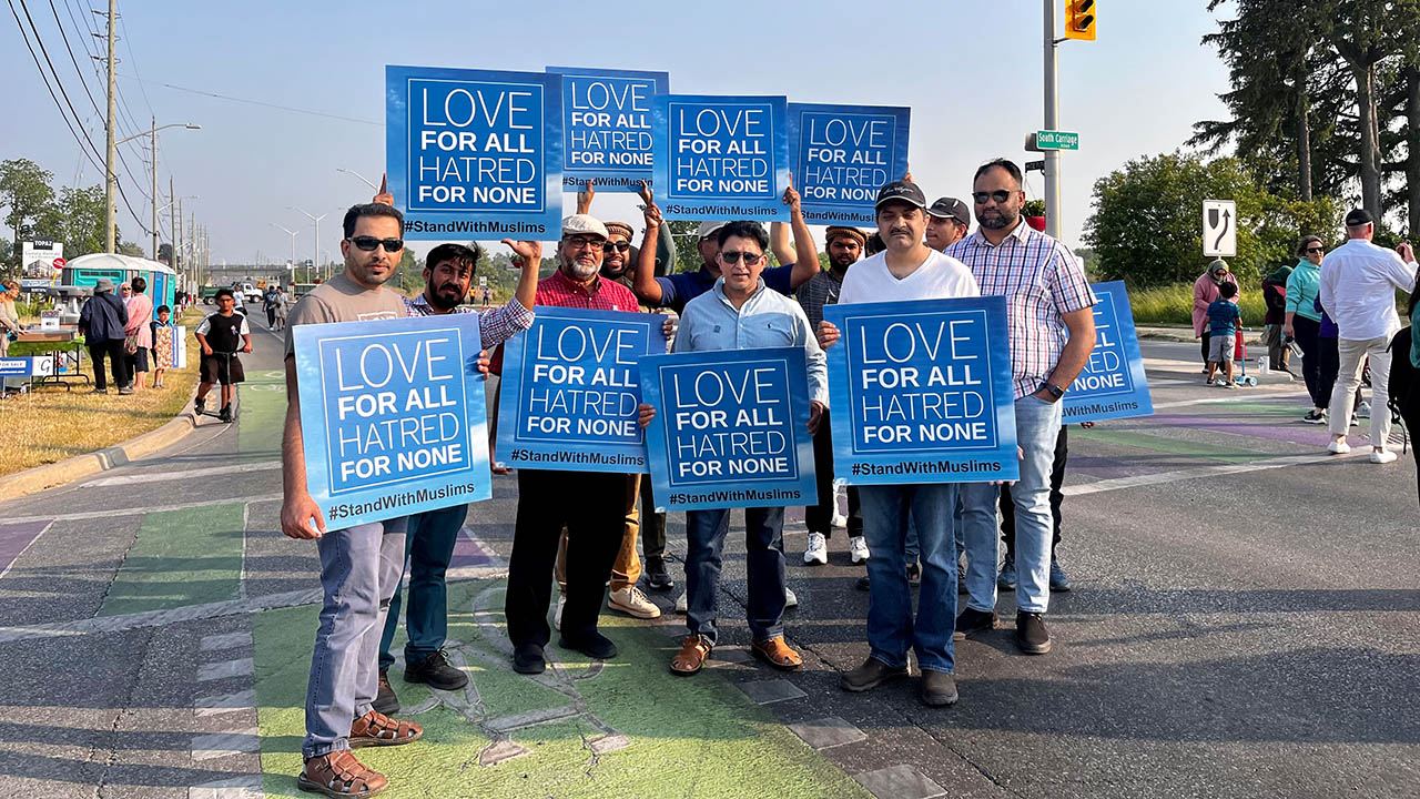 A group of people holding blue signs that state: Love for all, hatred for none. #StandWithMuslims