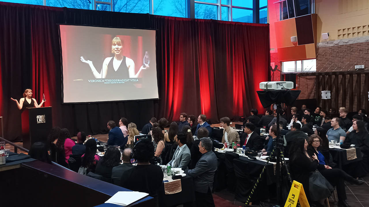 An award recipient is shown on stage, while crowd members watch on at the Fuel Awards at Fanshawe College.