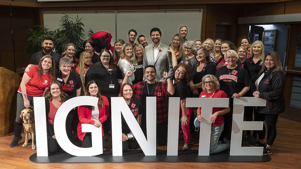 Several members of the Fanshawe community behind a sign that says, IGNITE