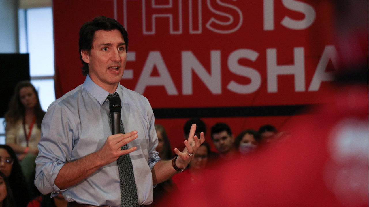Justin Trudeau speaking in front of a Fanshawe sign.