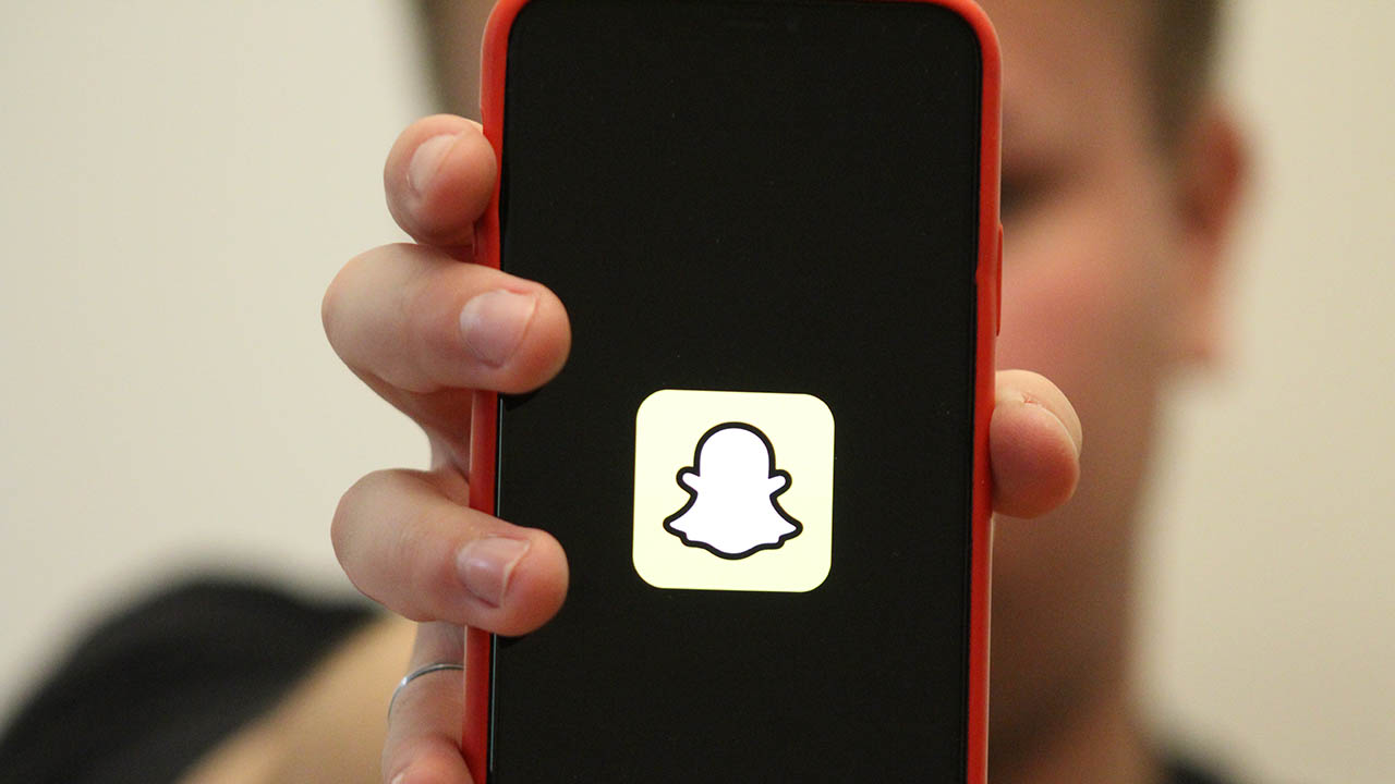 Person holding phone with a Snapchat logo on the screen.