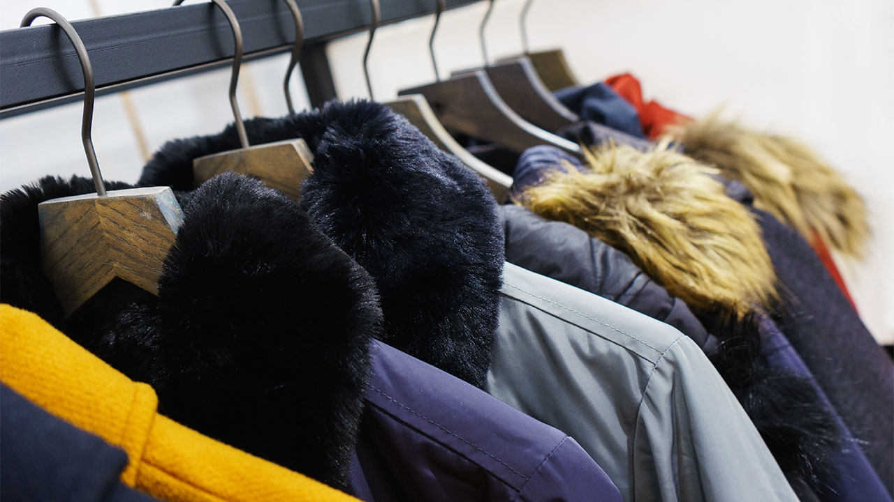 A series of winter coats hanging on a rack
