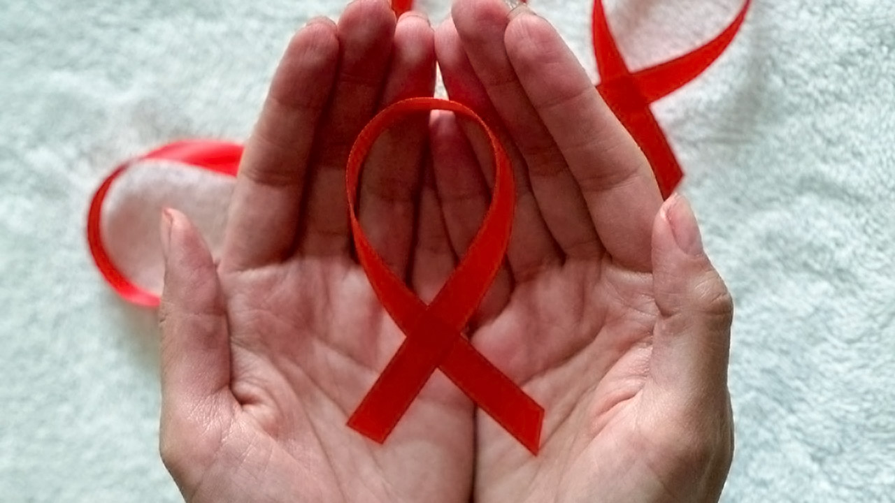 A photo of hands holding a red ribbon