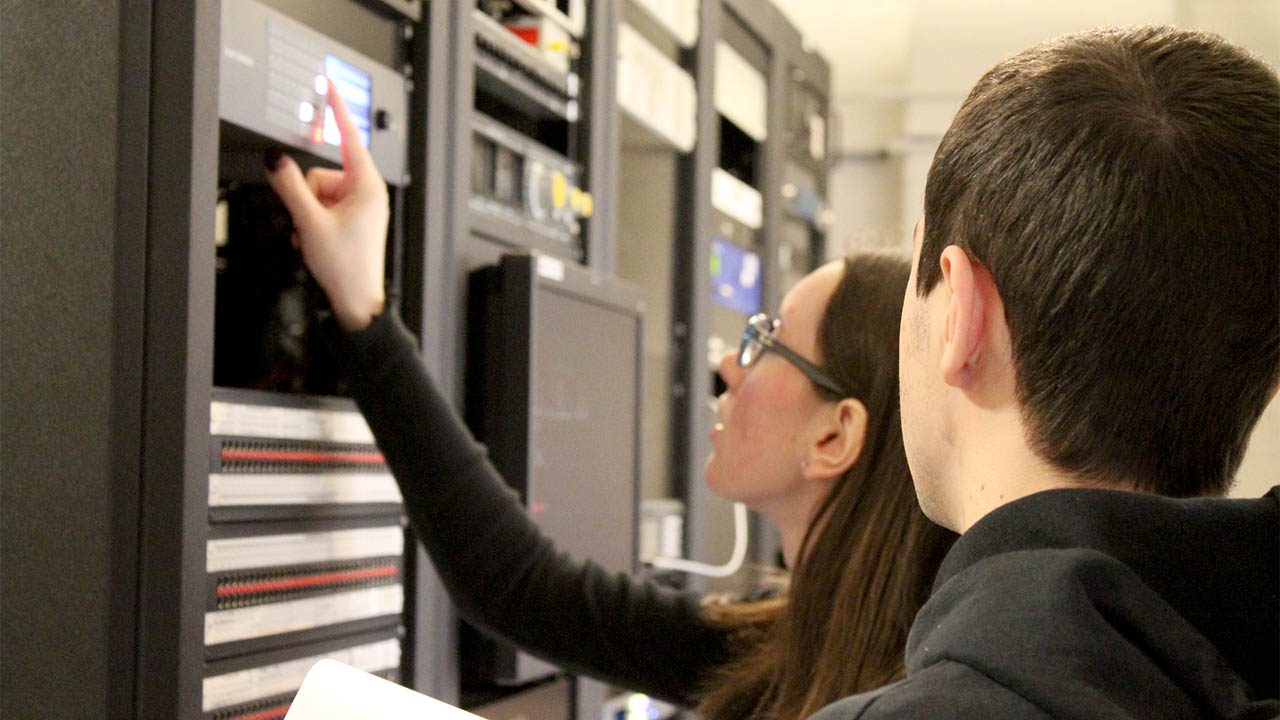 A student fixes a server in a control room at Fanshawe College.