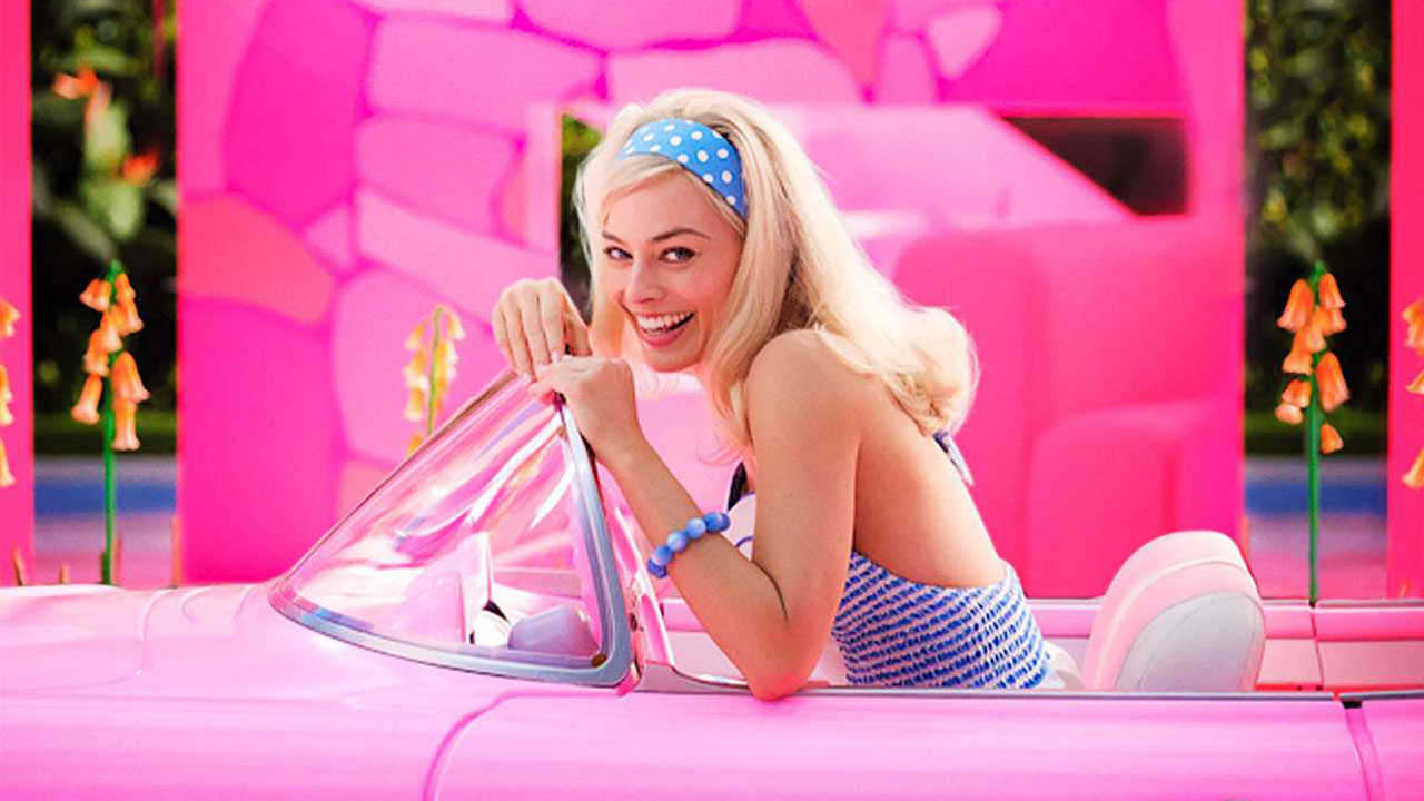A still from the Barbie movie showing actress Margot Robbie smiling in a pink car