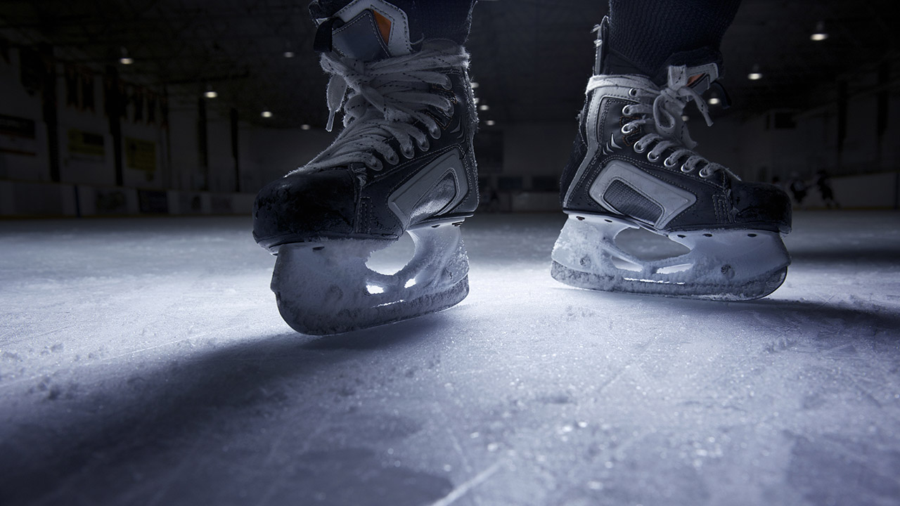 A stock image of hockey skates on an ice rink.