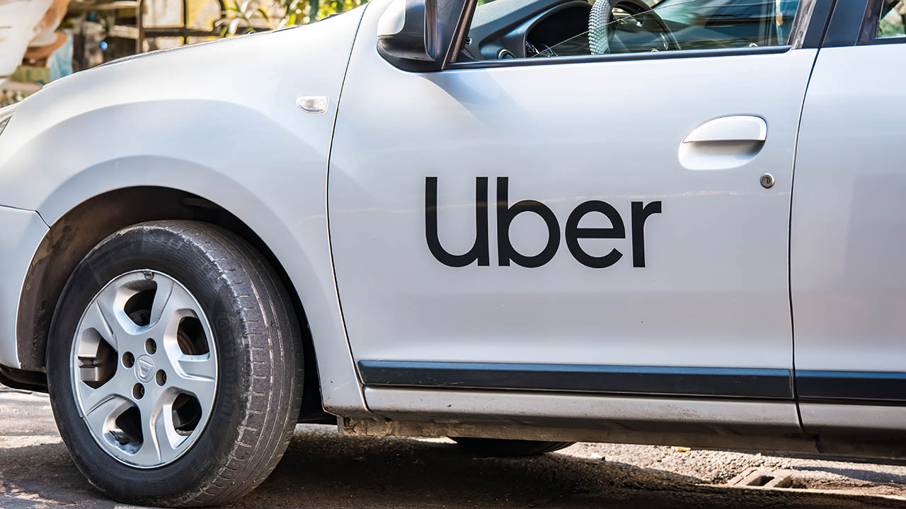 Stock photo of a white vehicle with the Uber logo embossed on the side.