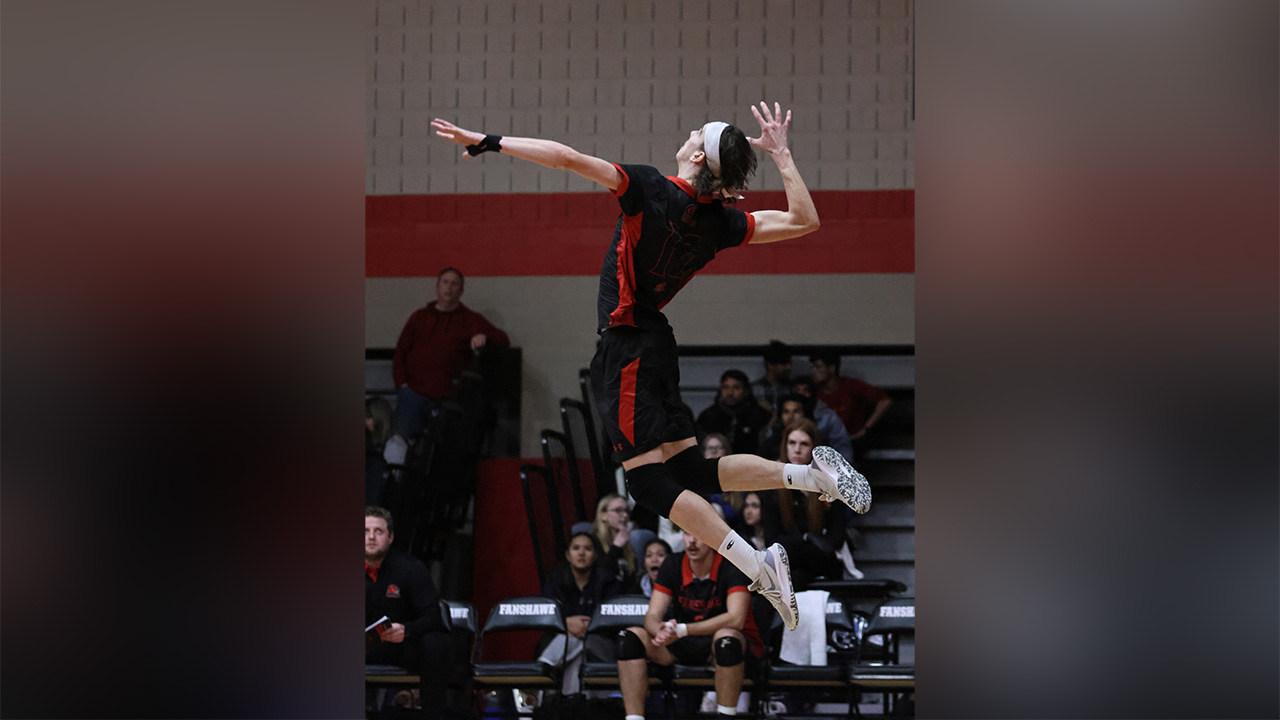 A photo of Daniel Ridings spiking a volleyball. 