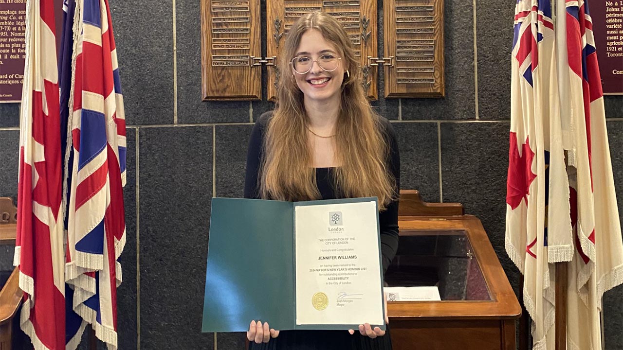 A photo of Jennifer Williams posing with her certificate from the Mayor's office. 