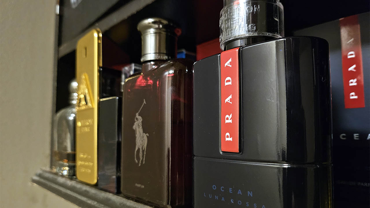 A photo of colognes on a shelf, including scents by Prada and Ralph Lauren.