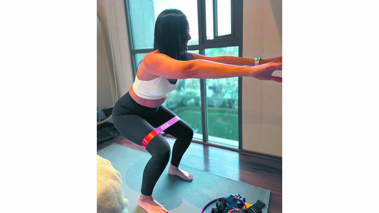 A photo of a woman performing squats with a resistance band in a small apartment.