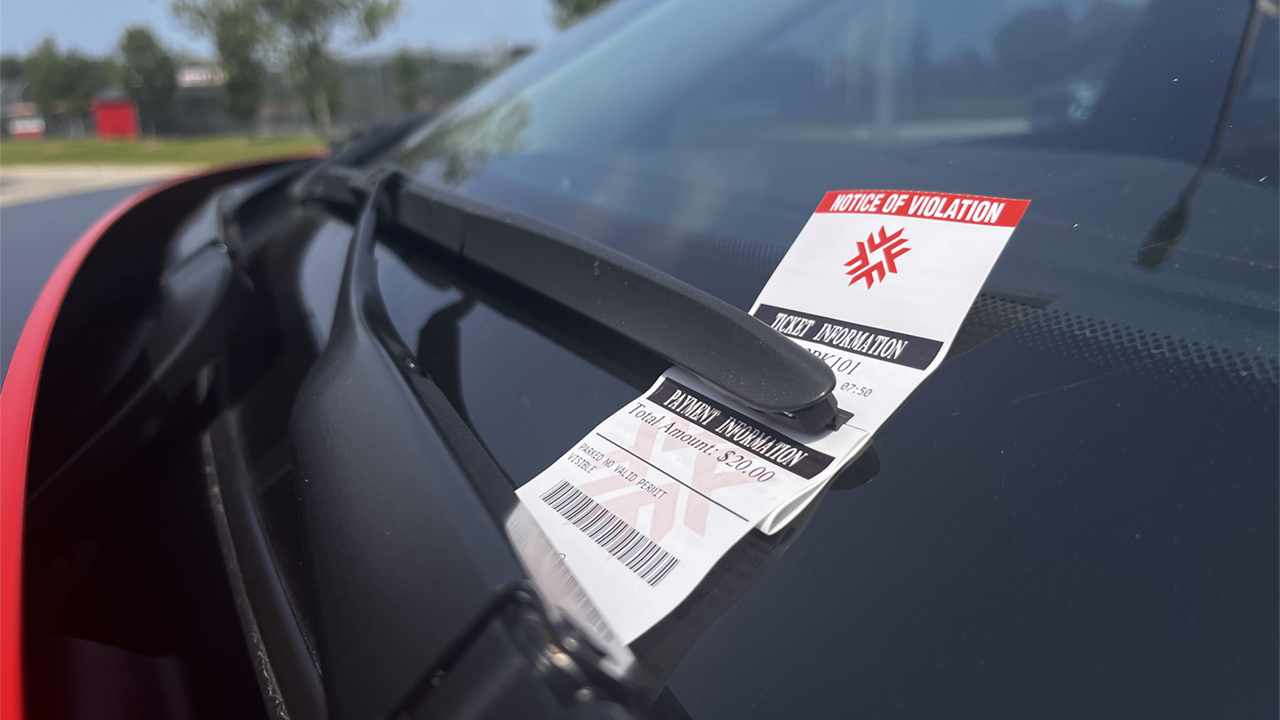 A photo of a parking ticket on the windshield of a parked car.