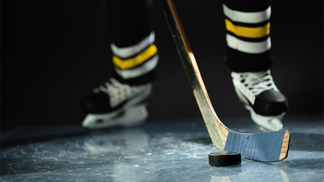 A photo of a hockey player on ice, handling the puck with a hockey stick
