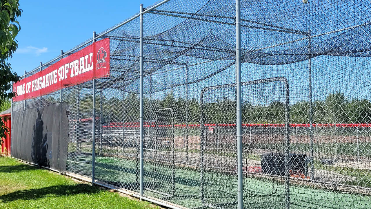 A batting cage with Fanshawe Falcons branding.