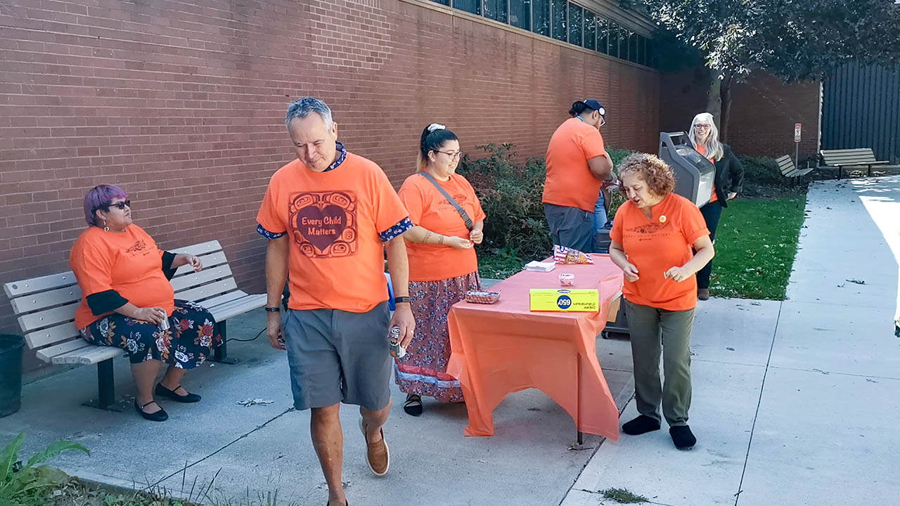 A photo of college staff wearing orange shirts at a barbeque