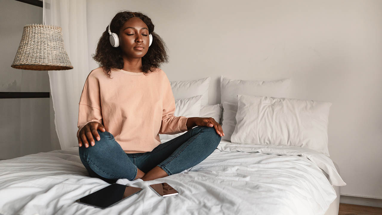 A photo of a woman meditating with headphones in.