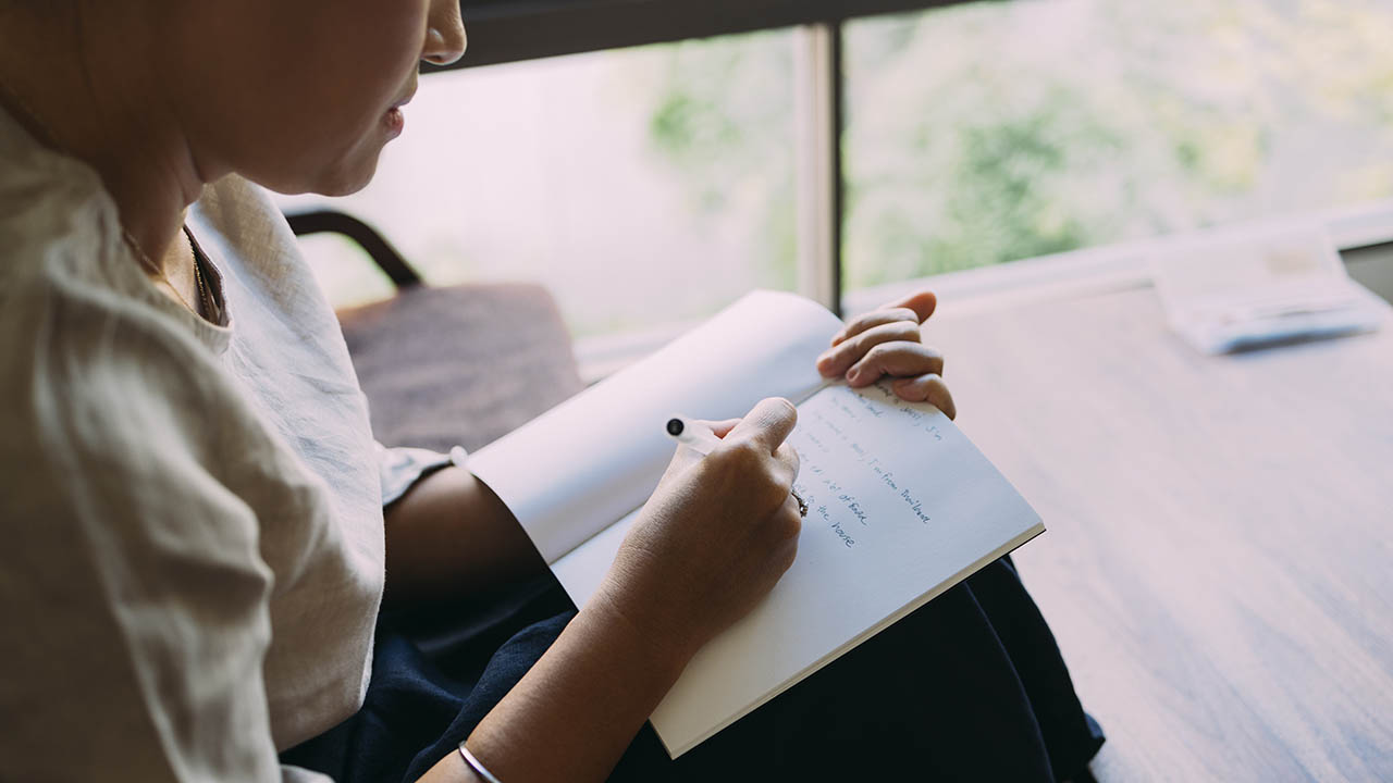 Stock photo of a woman writing in a journal.