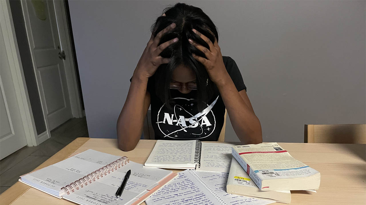 Someone with hands on hand, studying, looking stressed.