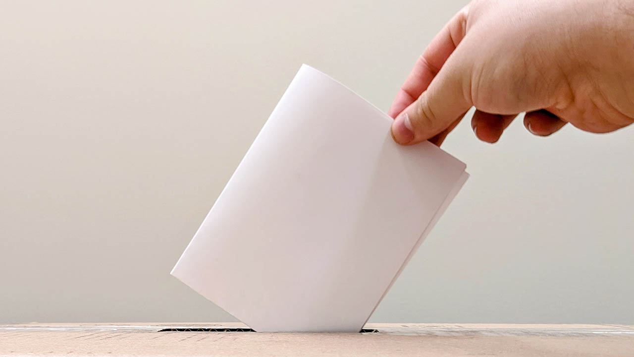 A ballot being put into a box.