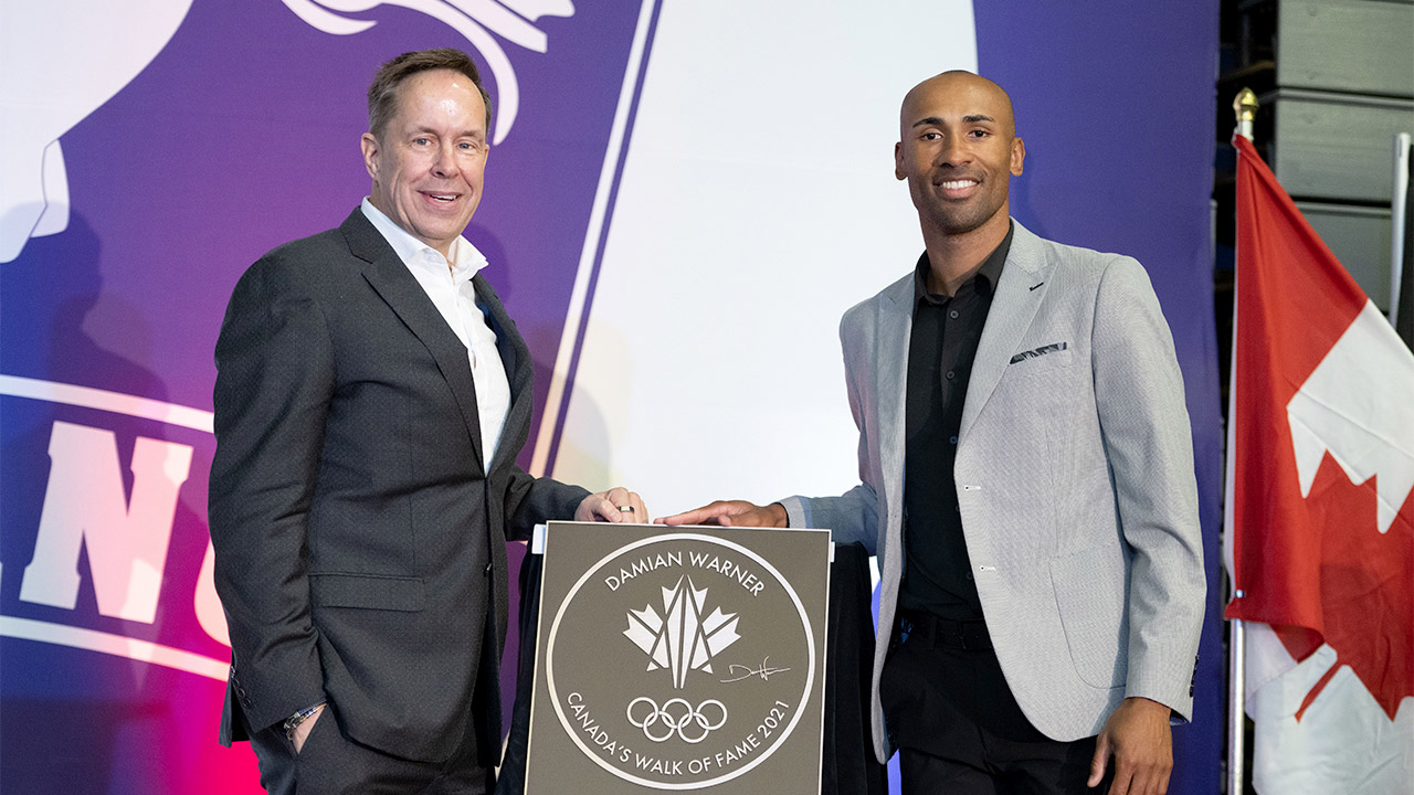 Photo of Jeffrey Latimer, chief executive of Canada's Walk of Fame, and reigning Olympic decathlon gold medalist Damian Warner standing with Warner's Canada's Walk of Fame plaque during a ceremony at Western University.