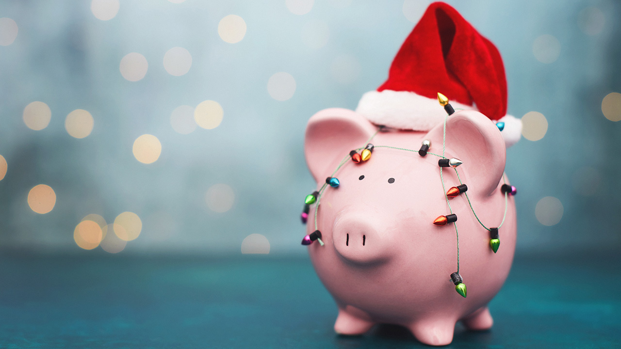Stock image of a piggy bank covered in Christmas lights and wearing a Santa hat