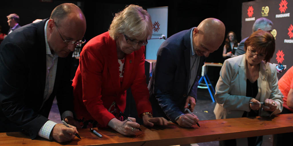 Attendees sign their names on one of the wooden joists to leave their mark